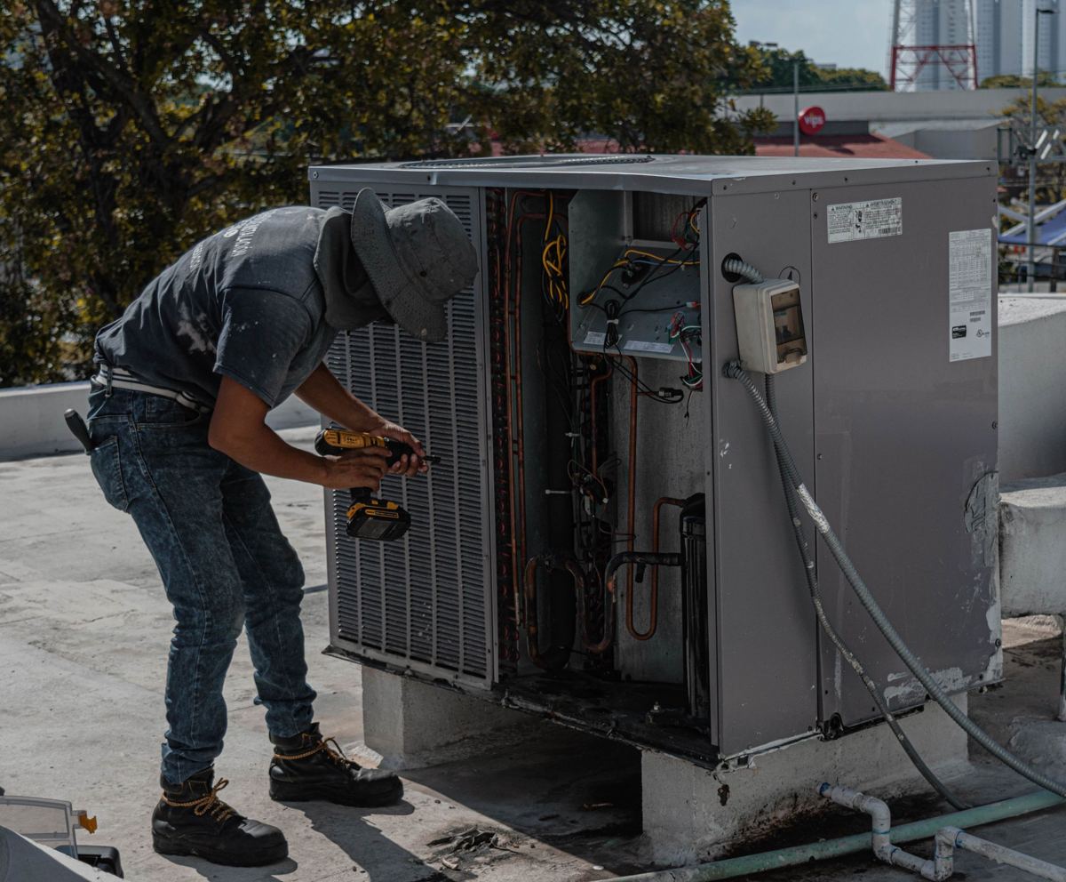 Technician repairing a rooftop air conditioning unit